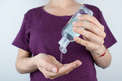 Midsection of woman holding purple against white background