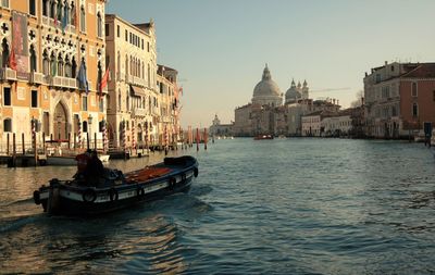 Boats in canal amidst city against clear sky