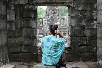 Rear view of woman sitting at angkor wat temple