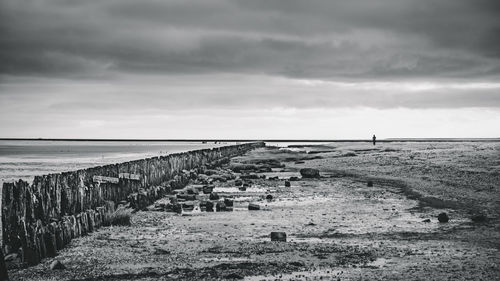 Wooden posts on beach by sea against sky