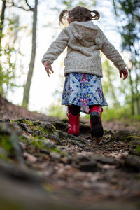 Low angle view of girl walking on forest trail.