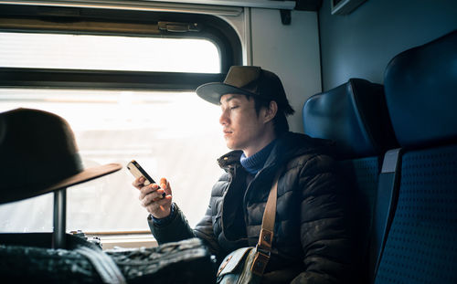 Man using mobile phone while sitting in train