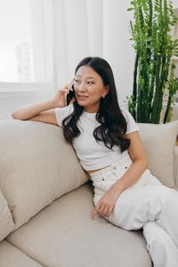 Young woman sitting on bed at home