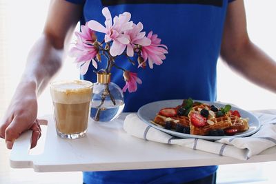 Midsection of woman holding ice cream in plate on table