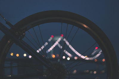 Low angle view of illuminated ferris wheel against sky at dusk