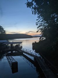 Pier on lake against sky during sunset
