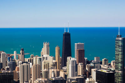 Modern buildings by sea against sky in city