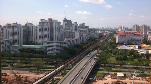 Aerial view of road and railroad track amidst buildings on sunny day in city