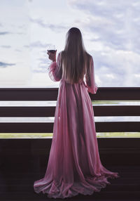 A beautiful girl with long white hair in a pink transparent negligee with a glass of red wine