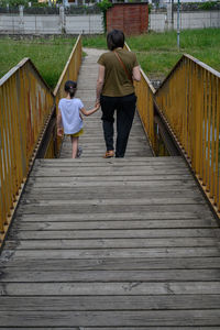 Rear view of people walking on footbridge