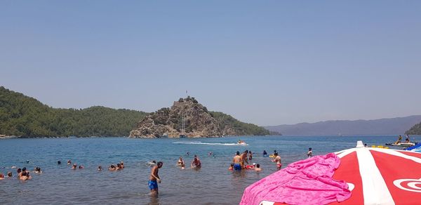 People on beach against clear sky