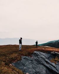 Rear view of two men standing on mountain against sky