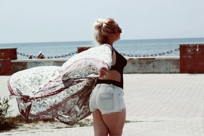 Side view of young woman standing at promenade