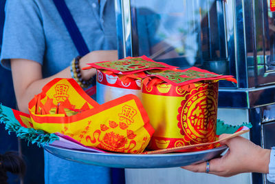 Midsection of woman holding multi colored umbrella