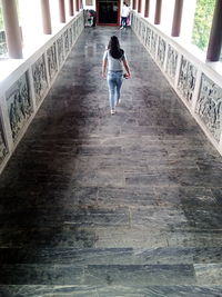 Full length rear view of woman walking on elevated walkway