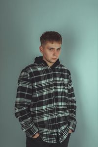 Portrait of young man standing against wall