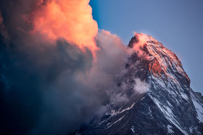 Midsection of man with red umbrella against sky