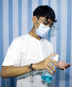 Man wearing mask washing hand with sanitizer