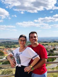 Portrait of young couple standing against sky