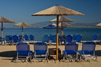 Chairs on beach by sea against sky