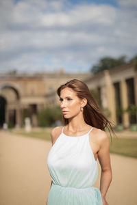 Young woman looking away while standing outdoors