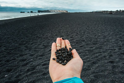 Close up woman showing handful of black pebbles on beach concept photo