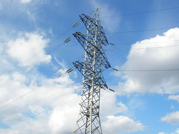 Low angle view of electricity pylon against cloudy sky