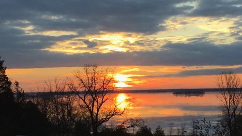 Scenic view of lake against cloudy sky during sunset