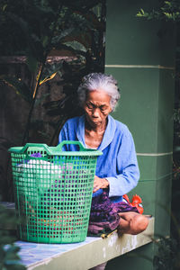 Woman sitting by laundry in container