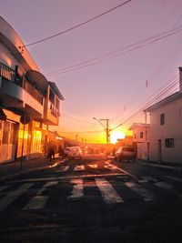 Street amidst buildings against sky during sunset