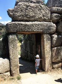 Rear view of boy standing against old ruin