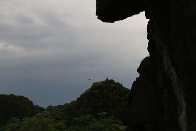 Rock formation amidst silhouette trees against sky