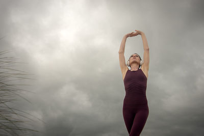 Low angle view of woman exercising against sky