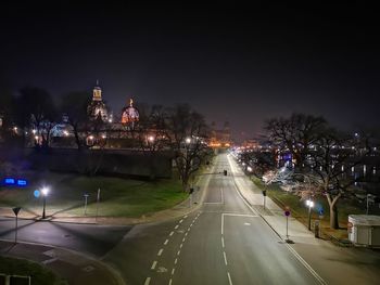 Illuminated city street against sky at night