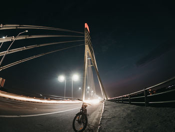 Light trails on bridge against sky at night