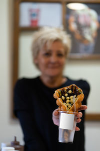 Portrait of woman holding sweet food at home