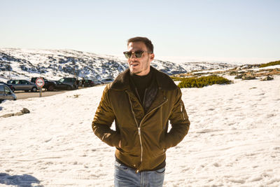 Young man wearing sunglasses while standing on snow covered field