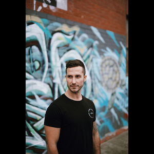 Portrait of young man standing against graffiti wall