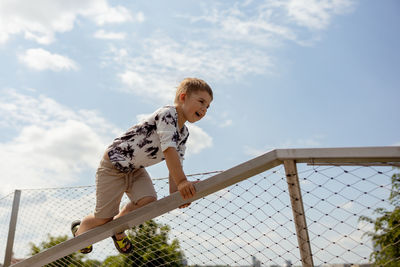 Adorable caucasian boy climbing on metal handrail outdoor. cute child having fun in the city.