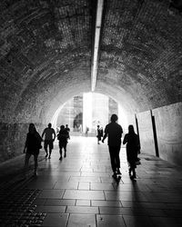 Rear view of silhouette people walking in tunnel
