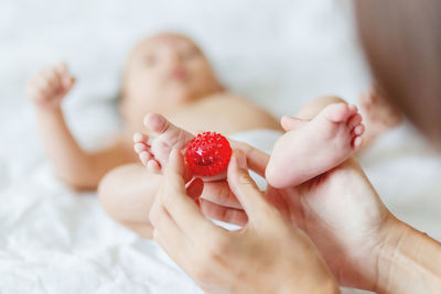 Cropped hands of mother holding toy on baby boy leg