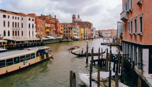 Boats moored in canal amidst city against sky