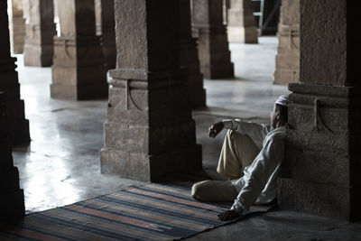 Muslim man leaning against column in monument