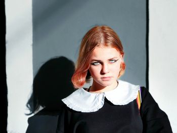 Portrait of a beautiful young woman standing against wall