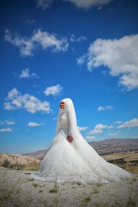 Woman standing on field against blue sky