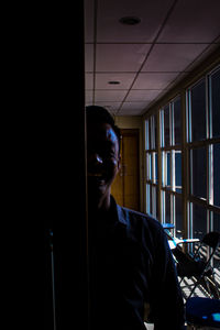 Portrait of young man looking through window