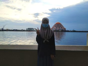 Rear view of woman standing by sea against sky