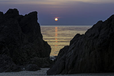 Rock formations in sea against sky during sunset