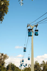 Low angle view of overhead cable car against blue sky