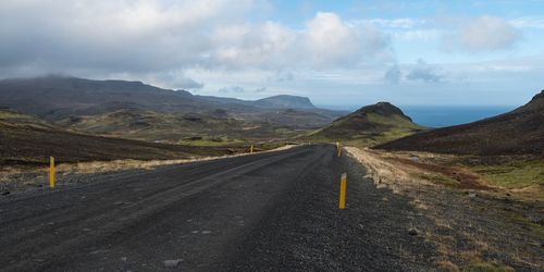 Scenic view of road by mountains against sky